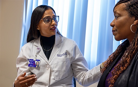 Doctor Arpi Thukral placing her hand on the shoulder of a female proton therapy patient.