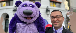 Sesame Street puppeteer Frankie Cordero standing next to his purple puppet Donkey Hodie