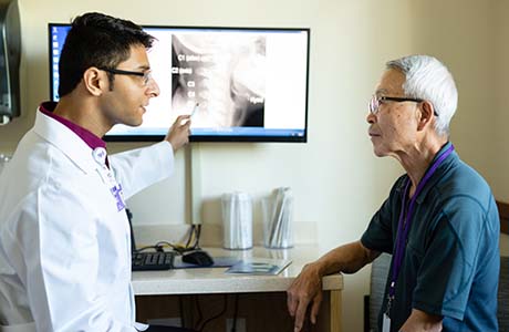 A male proton therapy physician pointing to a patient's scan.