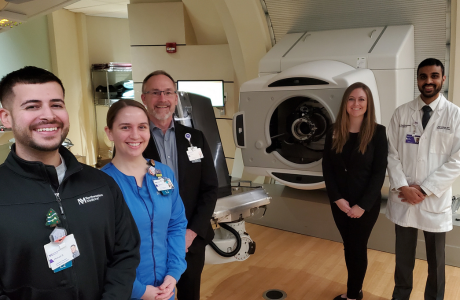 Northwestern Medicine Proton physicians and staff members smiling at the camera in a treatment room.