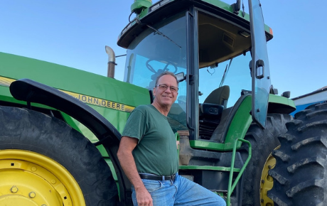 Northwestern Medicine Proton Center patient Lonnie standing by his tractor.