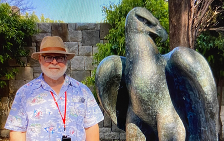 Northwestern Medicine Proton Center patient Michael standing next to a sculpture of an eagle.