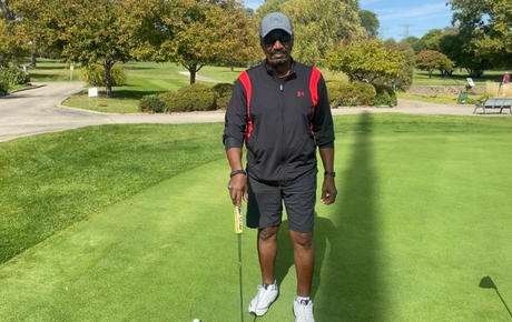 Proton therapy patient Sidney standing on a golf course holding a golf club on a sunny day.