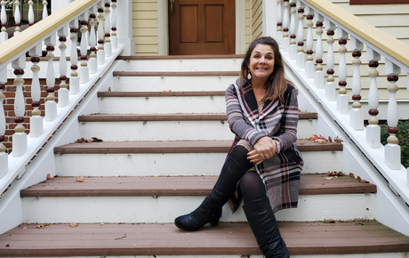 Proton therapy patient Wendy sitting on the front steps of a home.